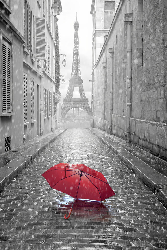 A red umbrella in a street with a tower in the background A red umbrella in a street with a tower in the background