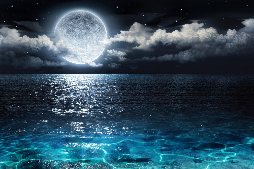A moon over water at night