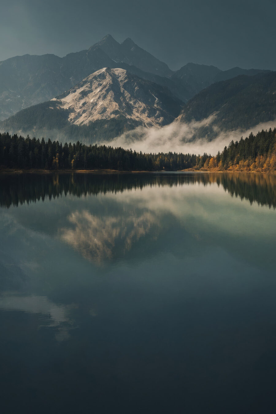 Jezero se stromy a horami v pozadí Jezero se stromy a horami v pozadí